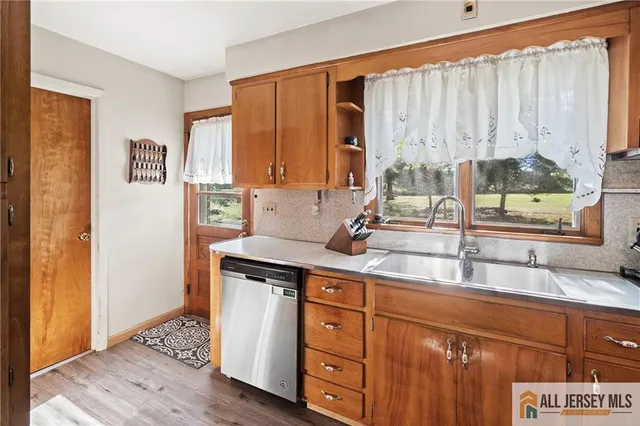 a kitchen with stainless steel appliances granite countertop a sink a stove and a wooden cabinets