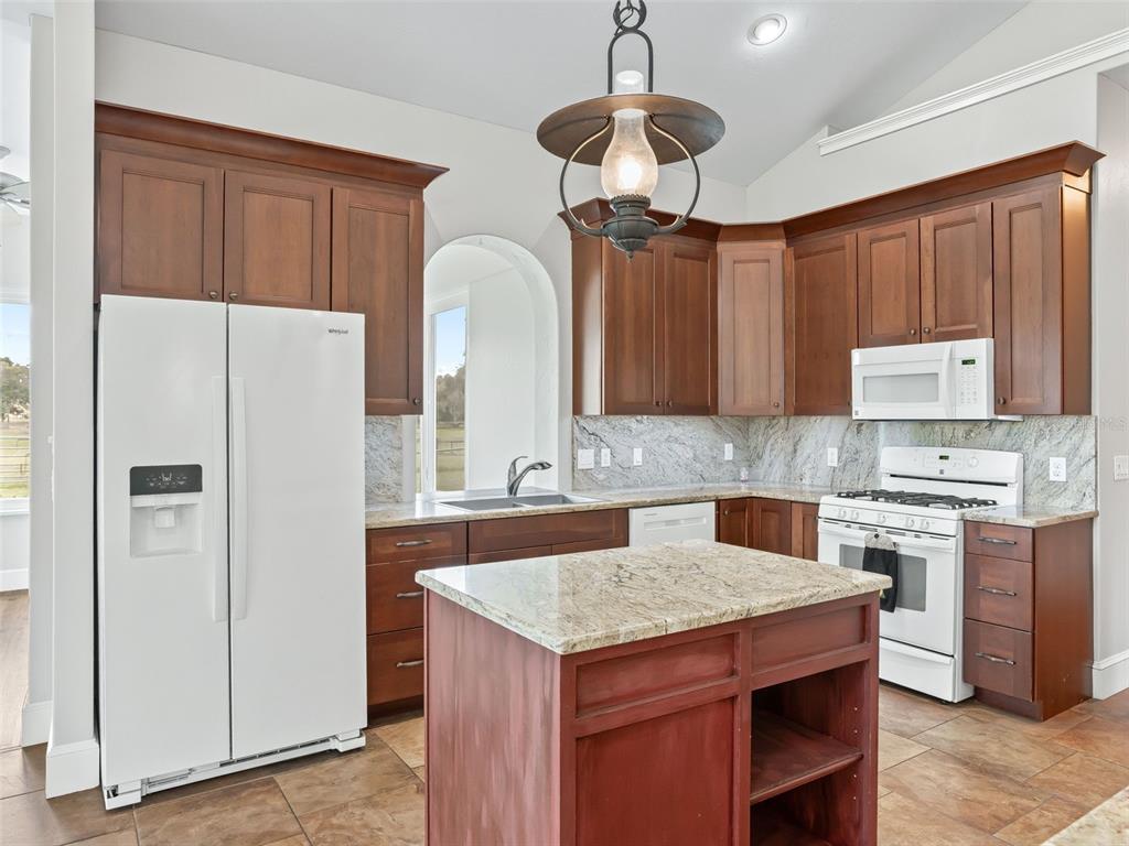 402 Southwest 127th Place Ocala, FL 34473 - Photo 17 of 75 a kitchen with stainless steel appliances granite countertop a refrigerator a sink dishwasher a stove with wooden cabinets and floor