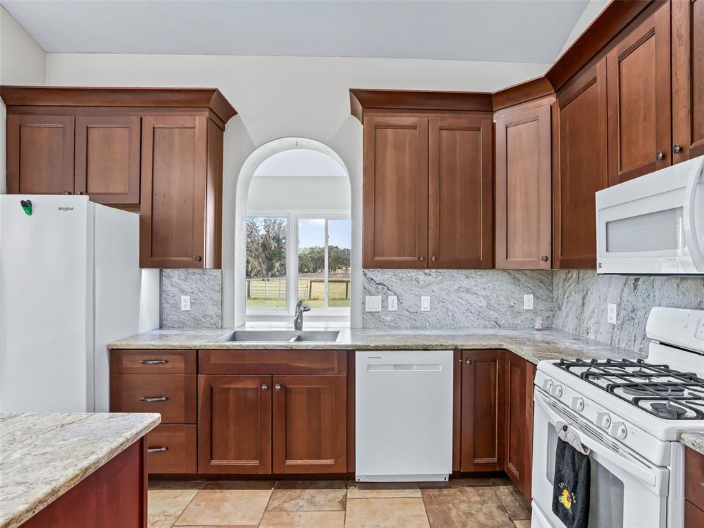 402 Southwest 127th Place Ocala, FL 34473 - Photo 18 of 75 a kitchen with stainless steel appliances granite countertop a stove a sink dishwasher and a refrigerator