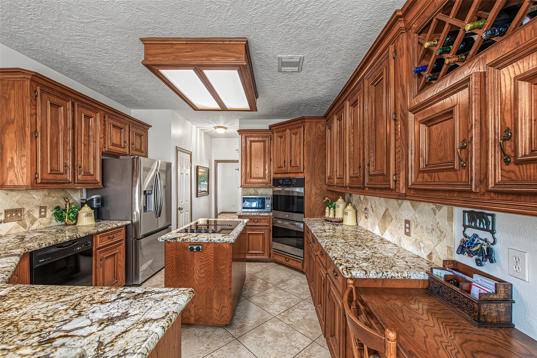 1345 Peach Ridge Road Brookshire, TX 77423 - Photo 23 of 50 Designed for both culinary precision and effortless entertaining, this chef’s kitchen features expansive granite countertops, rich solid-wood cabinetry, and a full suite of stainless steel appliances—including built-in double ovens and a central cooktop island.