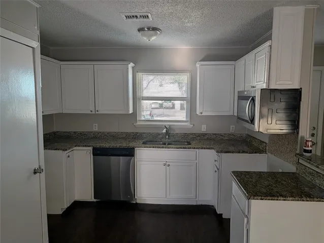 a kitchen with granite countertop a sink stove and cabinets