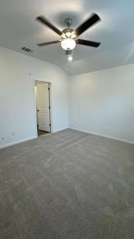 an empty room with a chandelier fan and windows