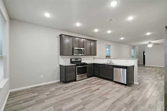 a large kitchen with stainless steel appliances kitchen island granite countertop a large counter top and wooden floors