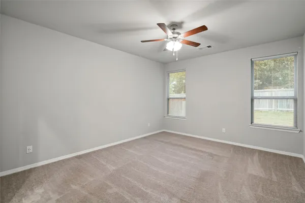 an empty room with windows and fan