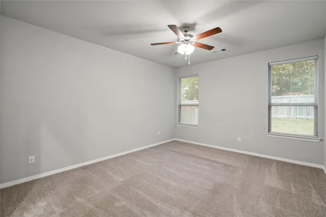 an empty room with windows and fan