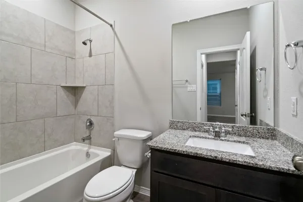 a bathroom with a granite countertop sink a toilet and bathtub