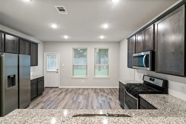 a kitchen with stainless steel appliances granite countertop a stove a sink and a refrigerator
