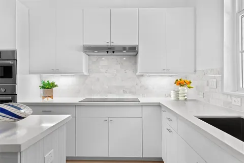 a kitchen with stainless steel appliances granite countertop white cabinets sink and stove
