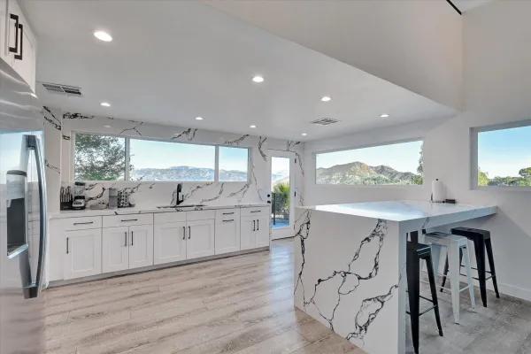 a kitchen with stainless steel appliances kitchen island granite countertop a table chairs sink and cabinets
