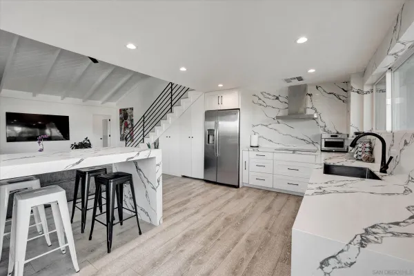 a kitchen with stainless steel appliances a sink a stove a refrigerator cabinets and a dining table with wooden floor