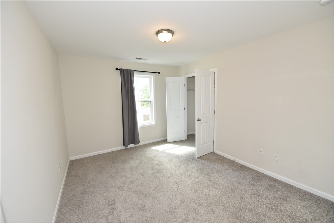 122 Bellflower Lane Anderson, SC 29625 - Photo 23 of 32 This spacious bedroom offers ample light and comfortable carpeted flooring, perfect for relaxation.