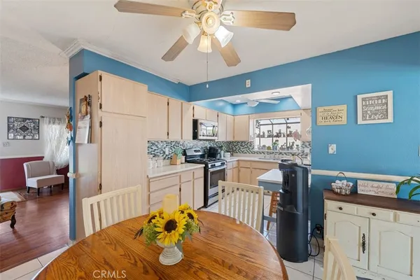 a kitchen with stainless steel appliances granite countertop a refrigerator a sink dishwasher a dining table and chairs with wooden floor