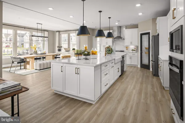 a kitchen with stainless steel appliances kitchen island granite countertop a stove a sink a refrigerator and white cabinets with wooden floor