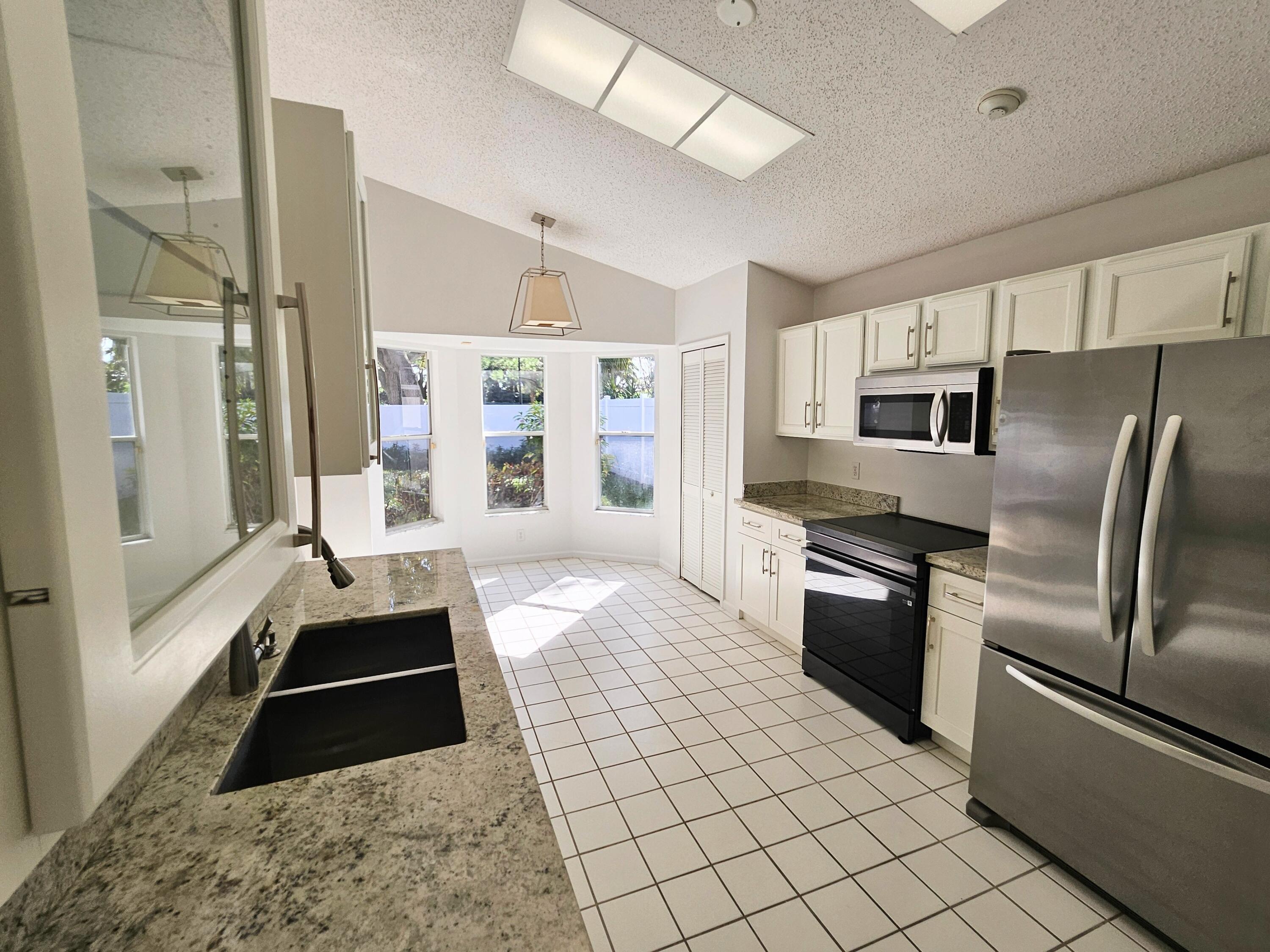 114 Spoonbill Court Jupiter, FL 33458 - Photo 5 of 12 a large kitchen with a stove a refrigerator and a sink