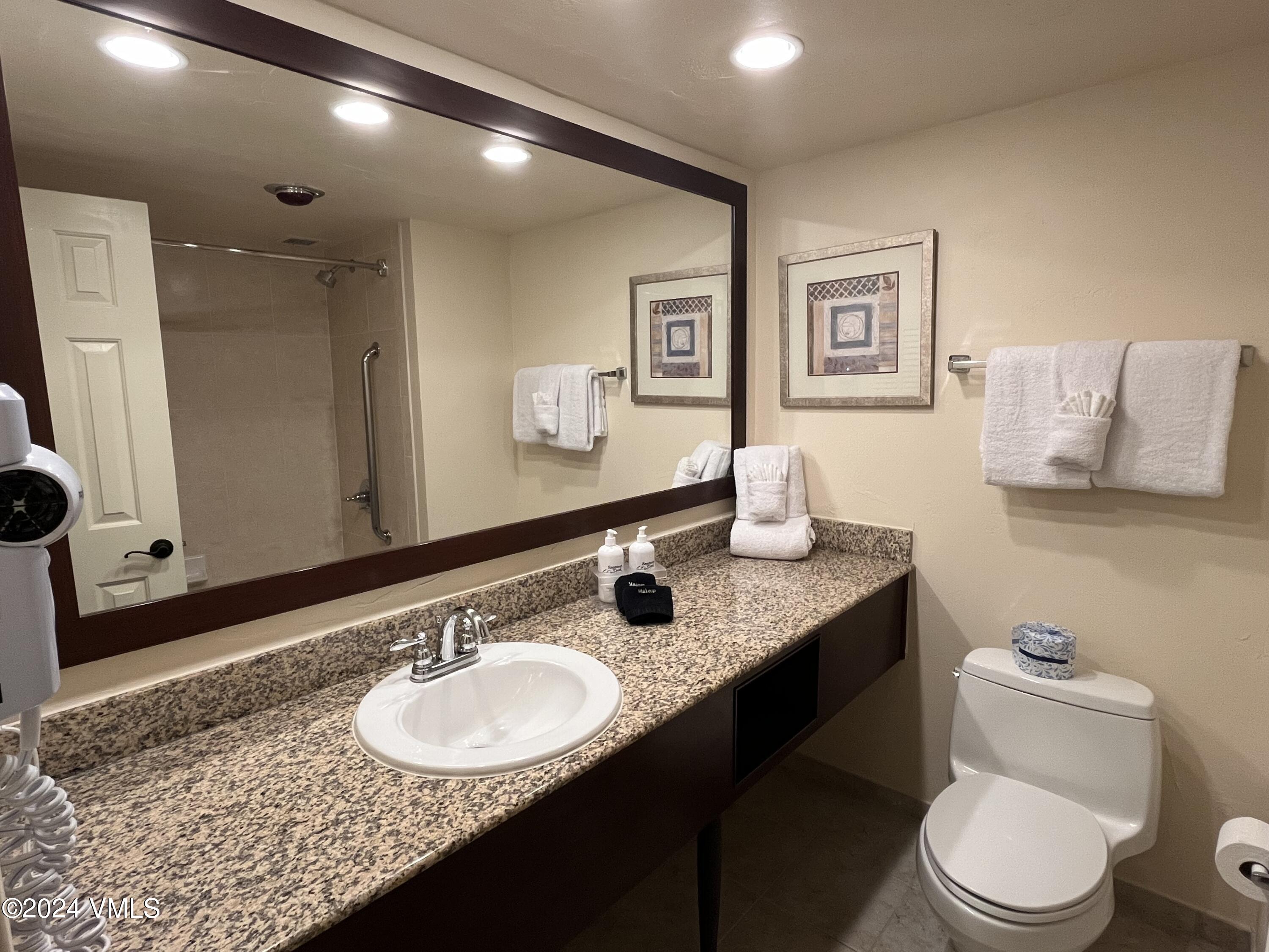 1020 Vail View Drive, Unit 310438 Vail, CO 81657 - Photo 14 of 25 a bathroom with a granite countertop sink a mirror and a toilet