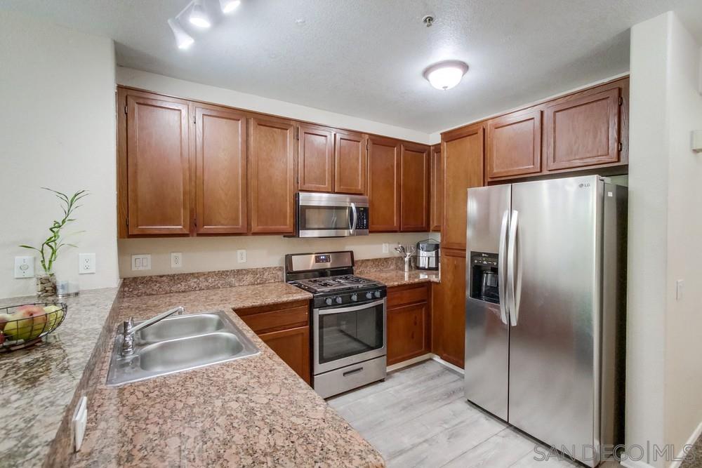 a kitchen with granite countertop stainless steel appliances a stove a refrigerator a sink a counter space and cabinets