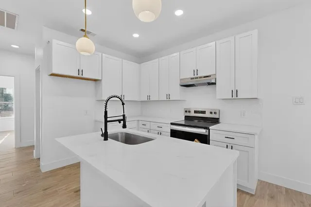 a kitchen with stainless steel appliances granite countertop a white stove top oven and cabinets