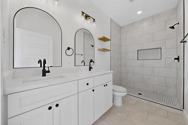 a bathroom with a double vanity sink toilet and a mirror