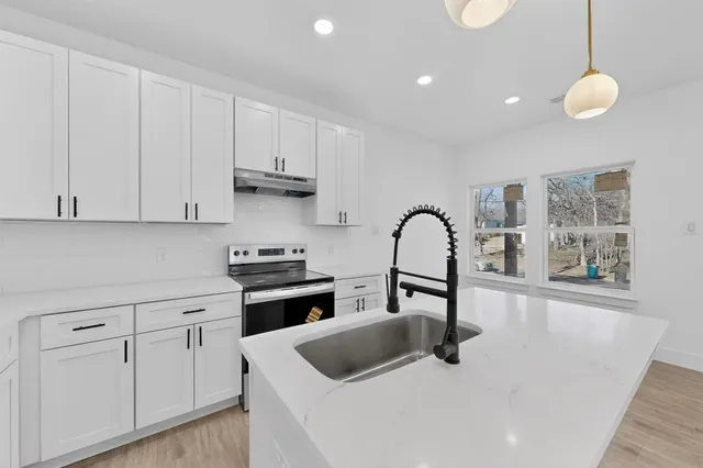 a kitchen with white cabinets and sink
