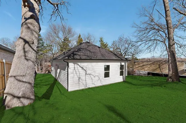 a white house with a small yard and large trees