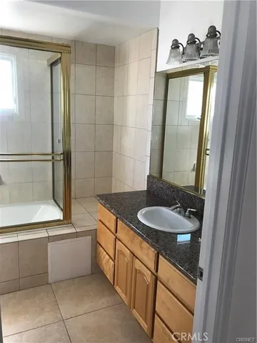 a bathroom with a granite countertop sink a mirror and a bathtub