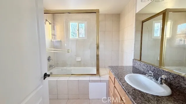 a bathroom with a granite countertop sink a mirror and a bathtub