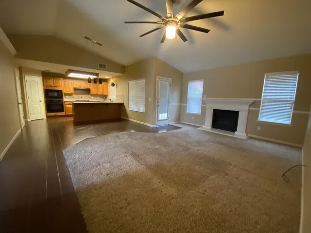 a view of a livingroom with a fireplace a ceiling fan and wooden floor