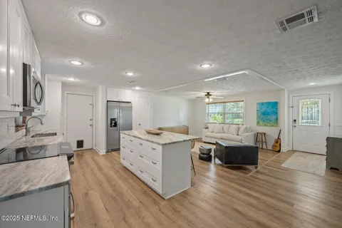 a large living room with stainless steel appliances granite countertop couches a fireplace and wooden floor