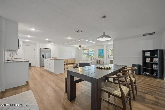 a view of a dining room and livingroom with furniture wooden floor a rug and a chandelier