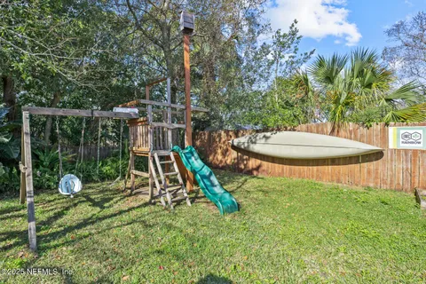 a view of a backyard with a slide trees and wooden fence