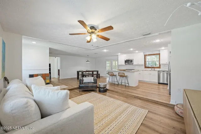 a living room with furniture and kitchen view with wooden floor
