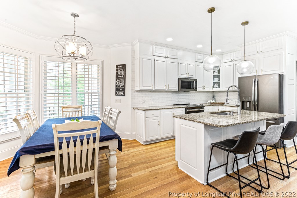 126 Falling Water Road Spring Lake, NC 28390 - Photo 24 of 47 a kitchen with stainless steel appliances granite countertop a stove a refrigerator a kitchen island a dining table and chairs