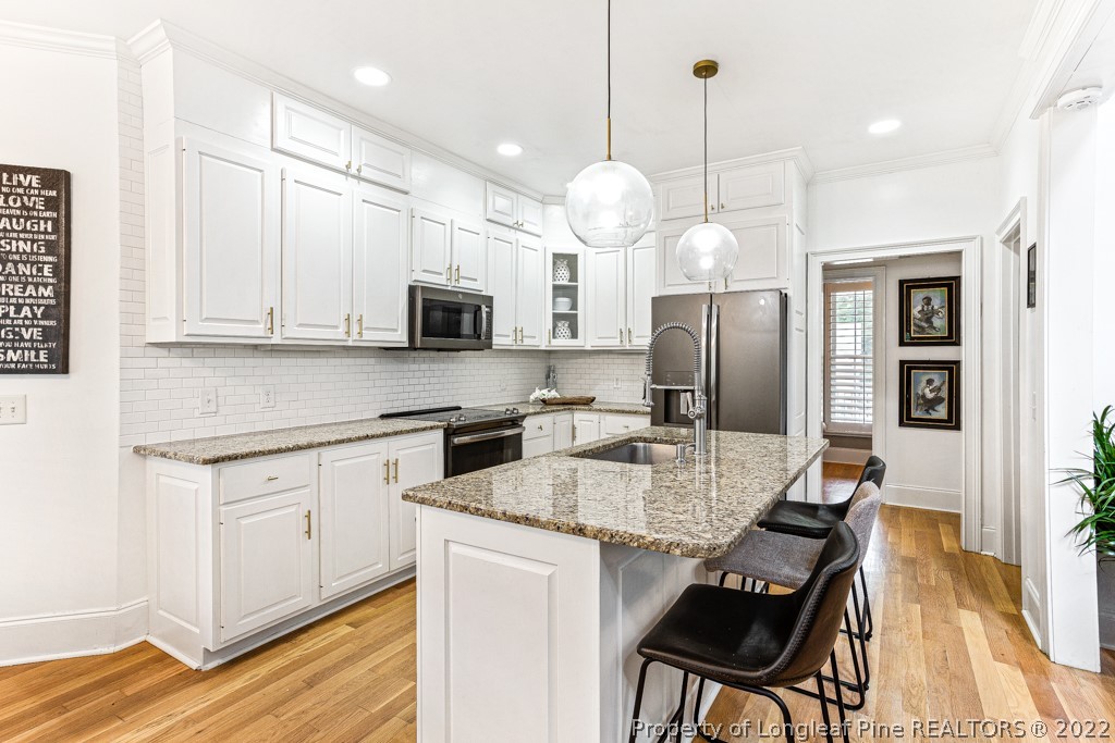 126 Falling Water Road Spring Lake, NC 28390 - Photo 27 of 47 a kitchen with a refrigerator a stove a sink dishwasher a dining table and chairs with wooden floor