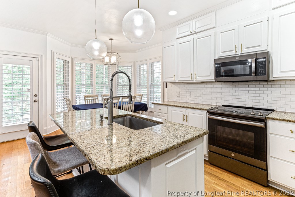 126 Falling Water Road Spring Lake, NC 28390 - Photo 29 of 47 a kitchen with stainless steel appliances granite countertop a stove top oven a sink dishwasher and white cabinets with wooden floor