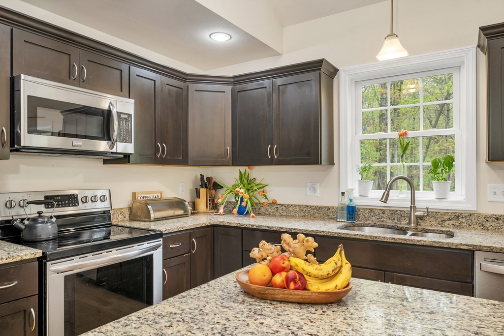 31 Danville Road Hampstead, NH 03826 - Photo 4 of 42 a kitchen with stainless steel appliances granite countertop a sink a stove a microwave and wooden cabinets