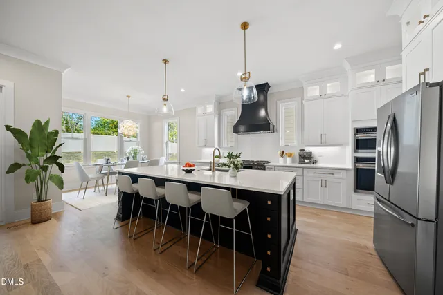a kitchen with stainless steel appliances a dining table chairs stove and white cabinets
