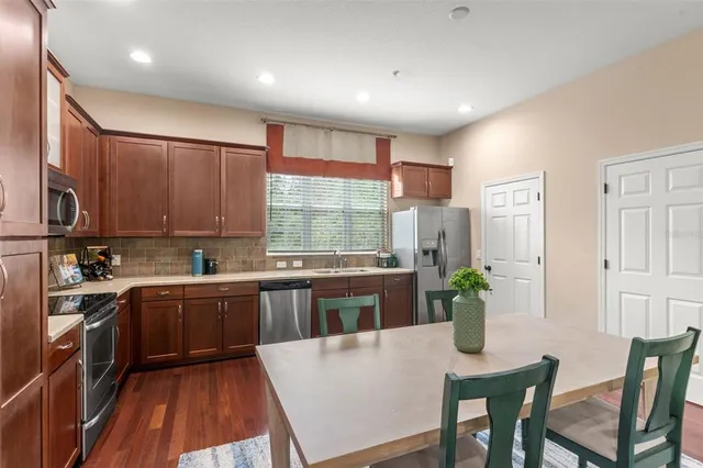 a kitchen with stainless steel appliances granite countertop sink stove refrigerator dining table and chairs