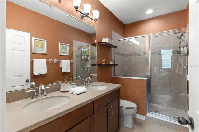 a bathroom with a double vanity sink toilet mirror and shower