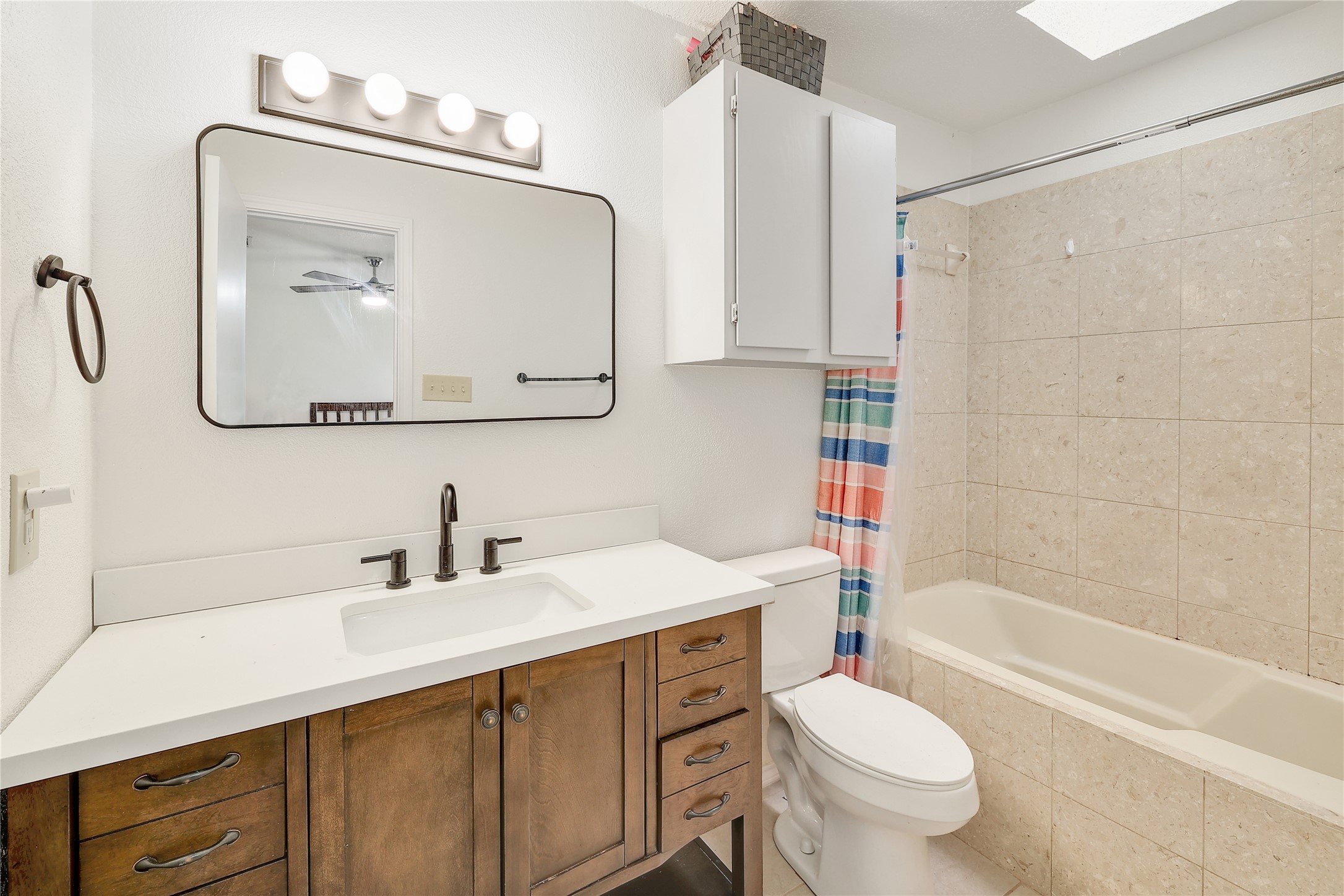 9906 Parliament House Road Austin, TX 78729 - Photo 20 of 33 Tiled surround walls and a wood-toned vanity highlight this clean bathroom design.