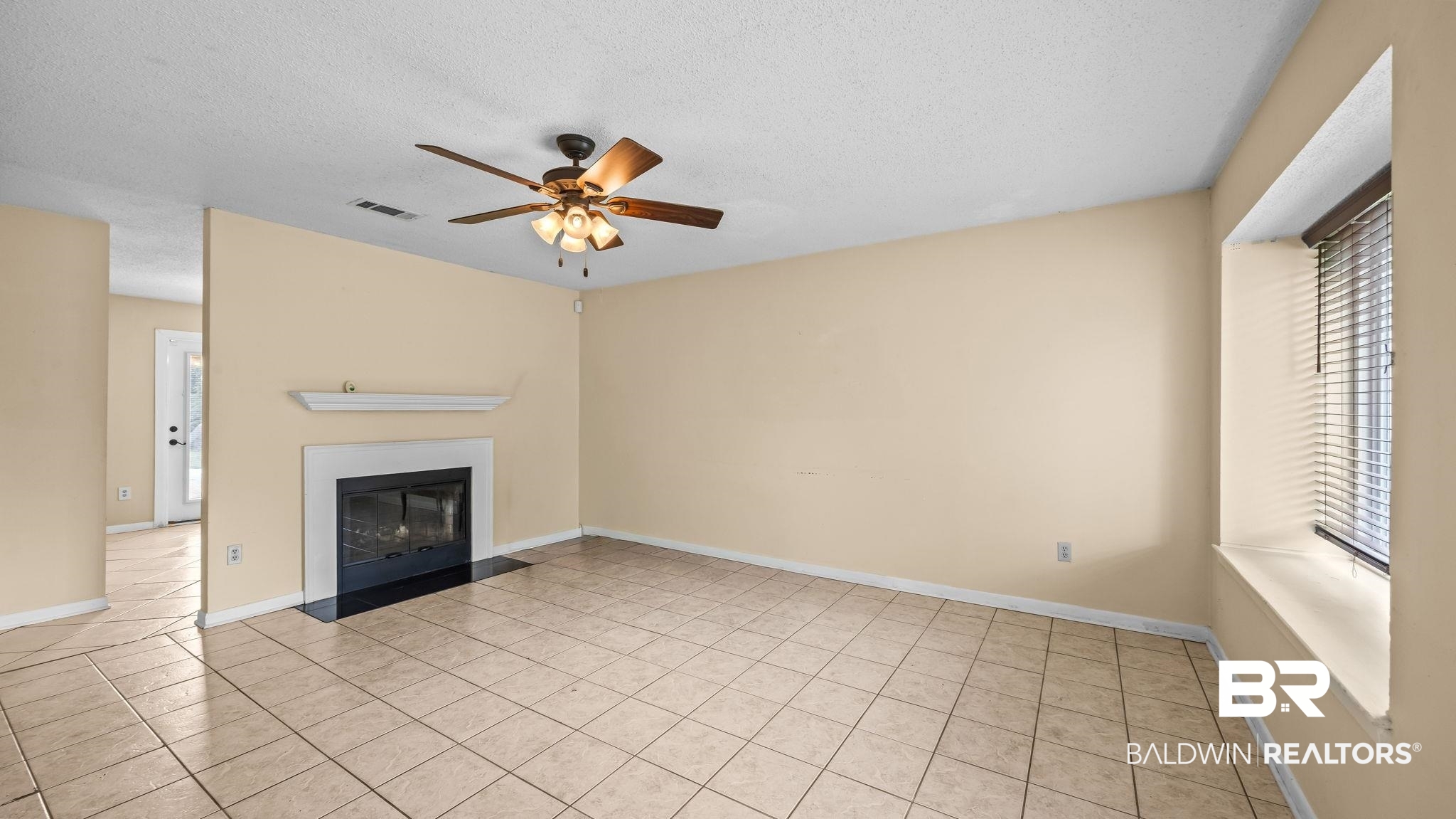15096 Highland Circle Foley, AL 36535 - Photo 9 of 52 Living area featuring large format tile flooring, a fireplace with a white mantel, and a ceiling fan with integrated lighting