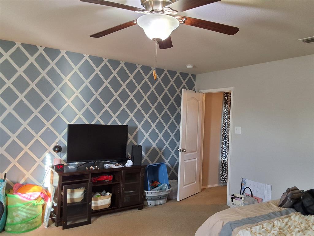 112 Hancock Street Venus, TX 76084 - Photo 20 of 25 Ceiling fan with light fixture, patterned accent wall, light-colored carpeting, and a paneled interior door