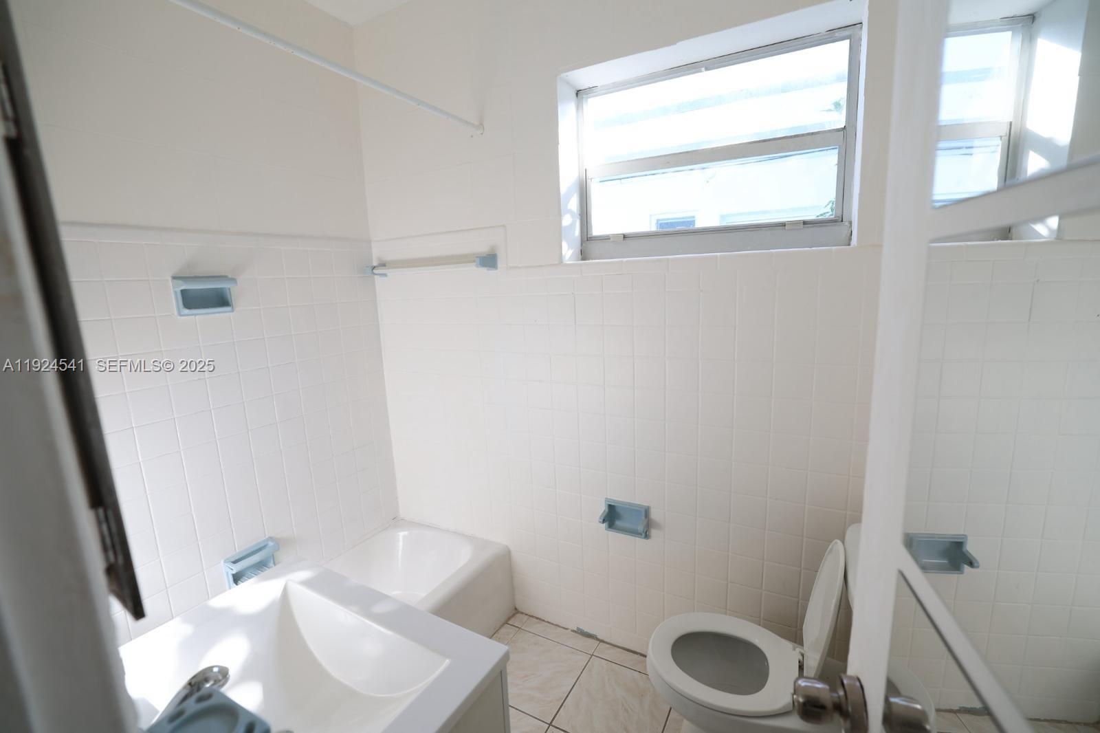 770 83rd Street, Unit 3 Miami Beach, FL 33141 - Photo 5 of 8 a white toilet sitting next to a bathroom sink