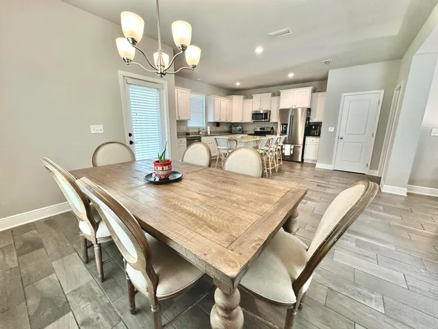 a dining room filled chandelier and wooden floor