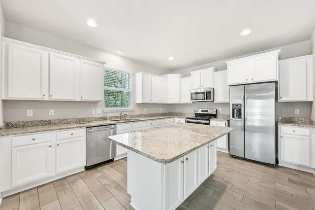 a kitchen with a sink stove a refrigerator and white cabinets