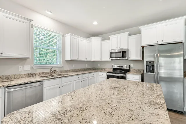 a kitchen with granite countertop a sink stainless steel appliances and window