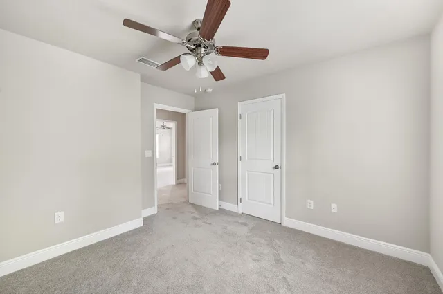 a view of an empty room and chandelier fan
