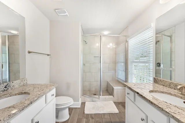 a bathroom with a granite countertop sink toilet a large mirror a shower and a bathtub
