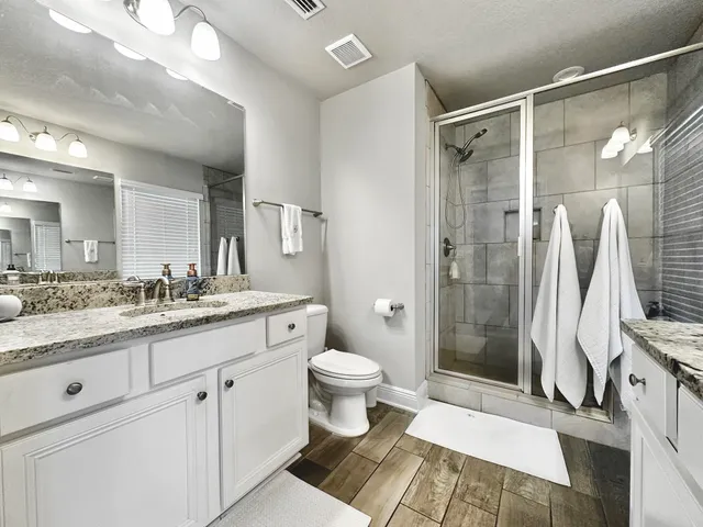 a bathroom with a granite countertop sink toilet and shower
