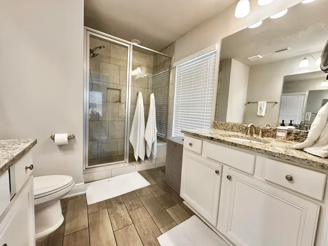 a bathroom with a sink a toilet a mirror and a shower