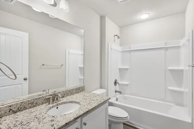 a bathroom with a granite countertop sink toilet tub and shower